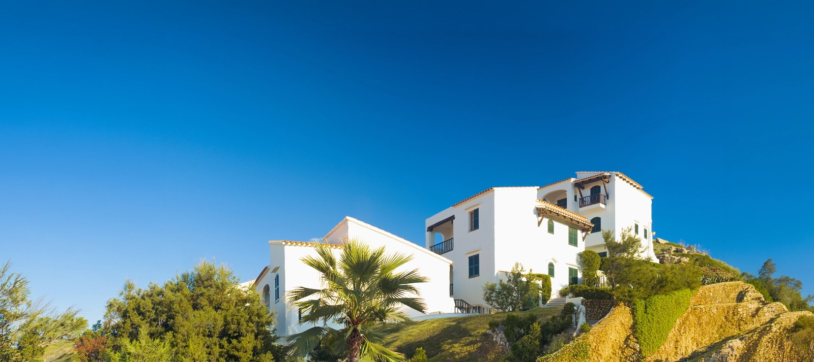 White villas with terracotta roofs on a hillside under a deep blue sky